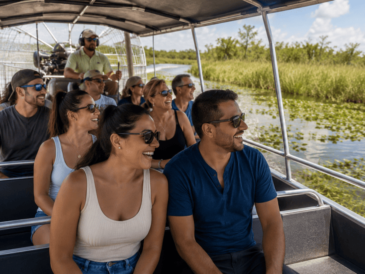 Group enjoying an airboat tour in a swamp with lush greenery.